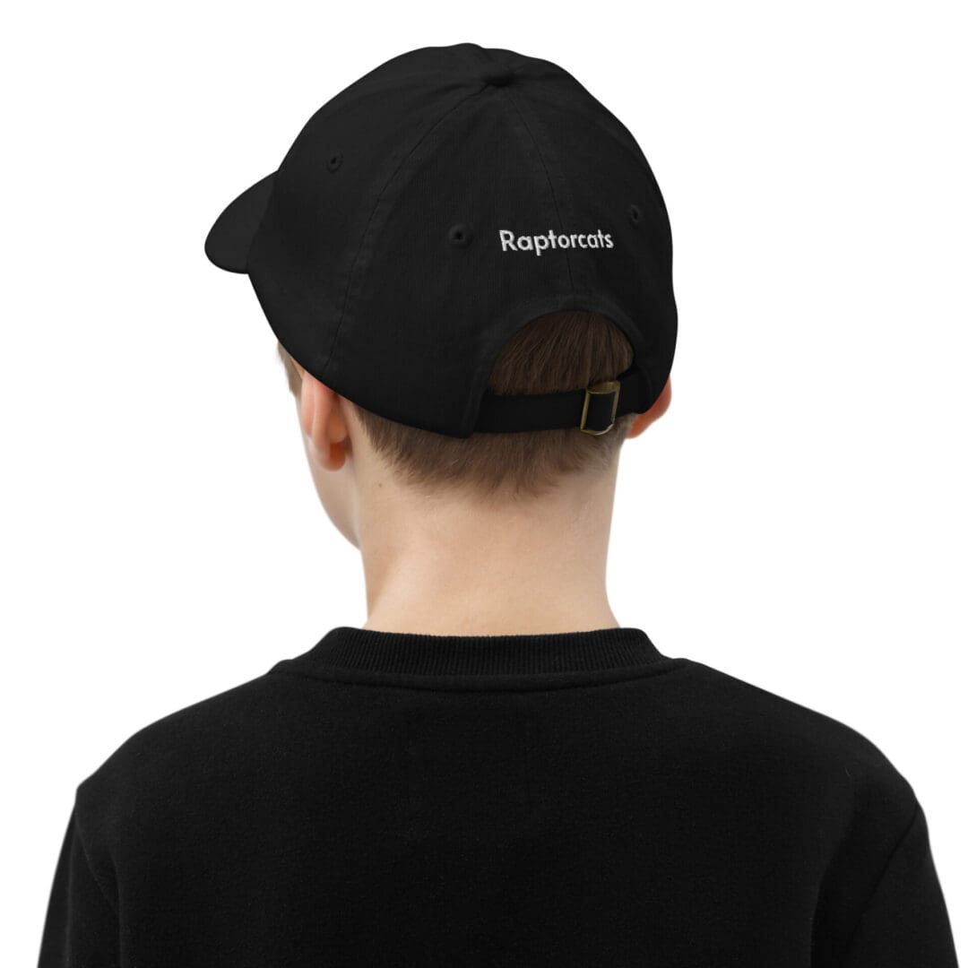 Boy wearing black cap with "Raptorcats" text.
