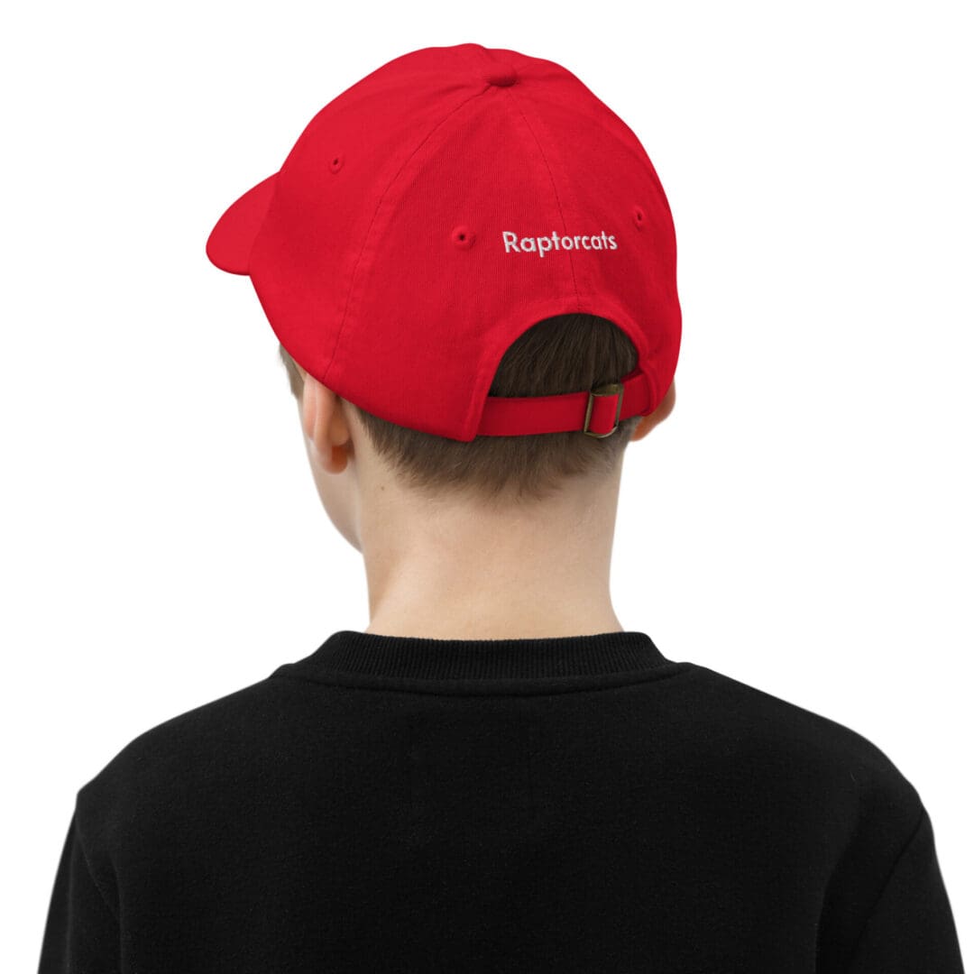 Child wearing red "Raptorcats" cap, black shirt.