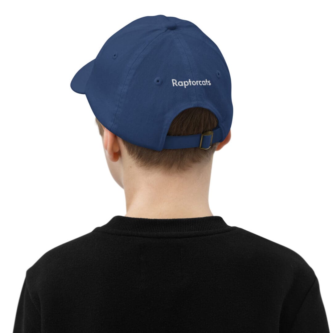 Boy wearing blue "Raptorcats" cap, black shirt.